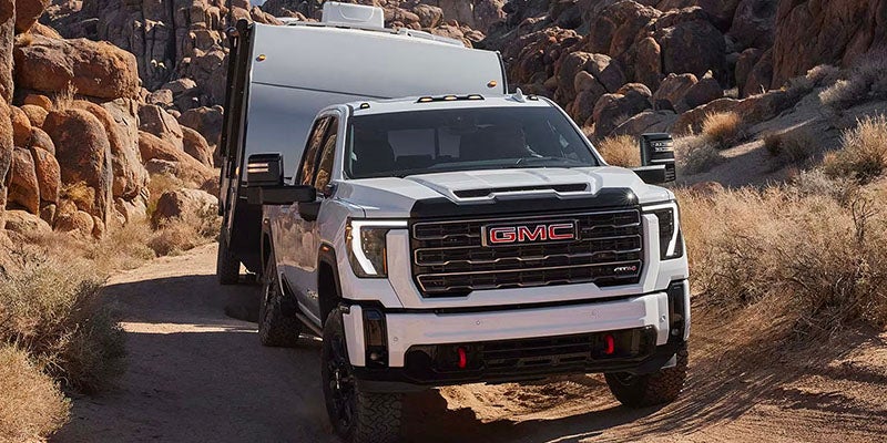 A white GMC pickup truck tows a large enclosed trailer