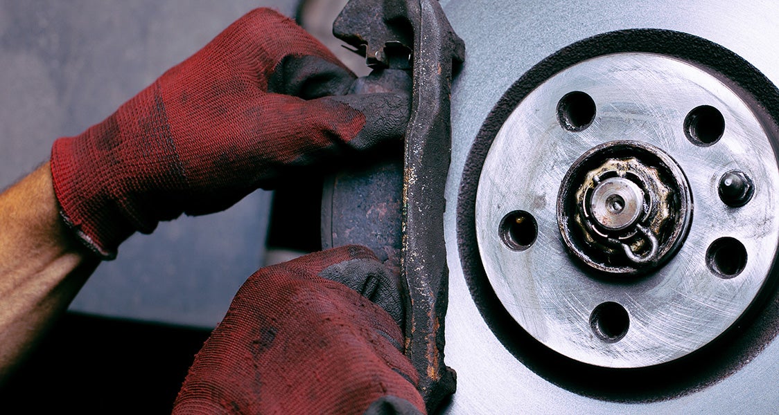 Close-up of gloved hands working on a vehicle’s brake assembly